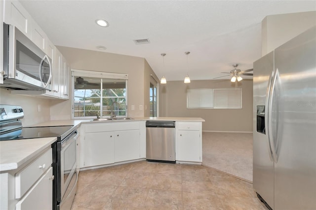 kitchen featuring decorative light fixtures, kitchen peninsula, sink, white cabinetry, and appliances with stainless steel finishes