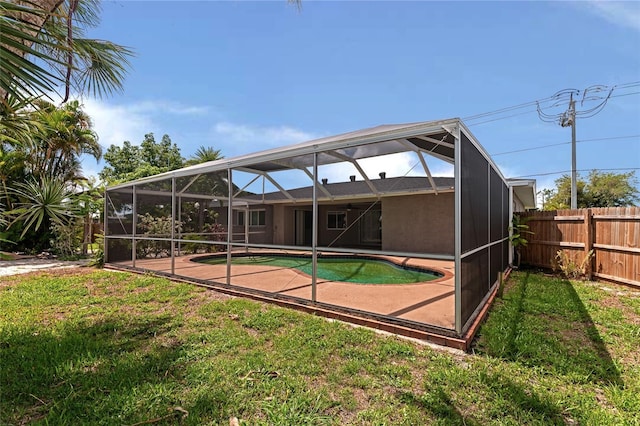 back of house featuring a fenced in pool, glass enclosure, a patio area, and a lawn