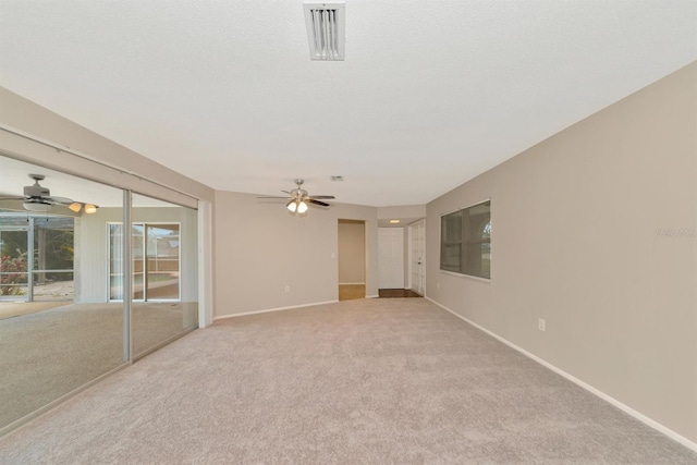 unfurnished room with ceiling fan, a textured ceiling, and light carpet