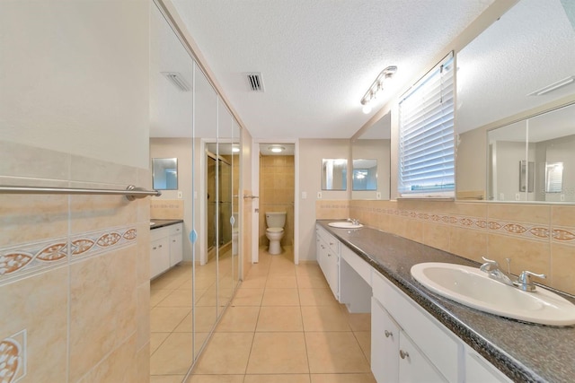 bathroom with toilet, vanity, tile patterned flooring, tasteful backsplash, and a textured ceiling