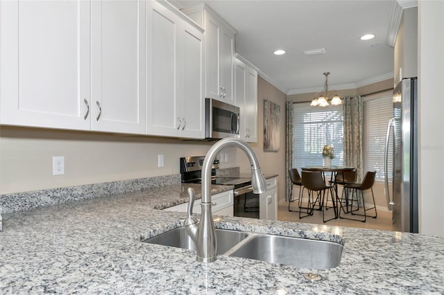 kitchen featuring sink, white cabinets, ornamental molding, stainless steel appliances, and light stone countertops