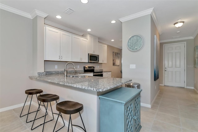 kitchen featuring white cabinetry, stainless steel appliances, a kitchen breakfast bar, and kitchen peninsula