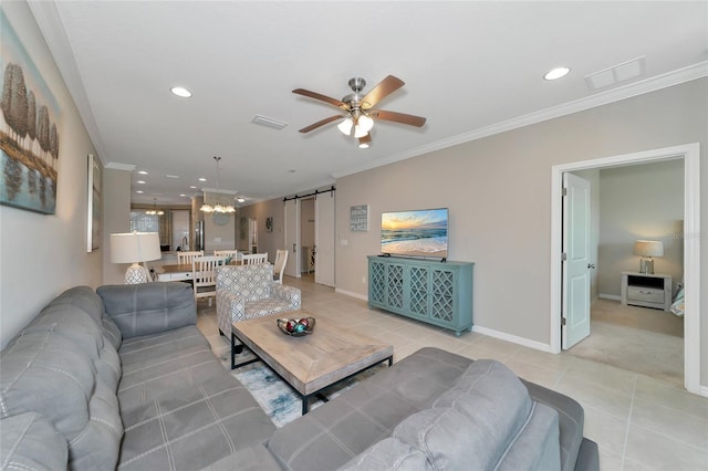 tiled living room with crown molding, a barn door, and ceiling fan with notable chandelier