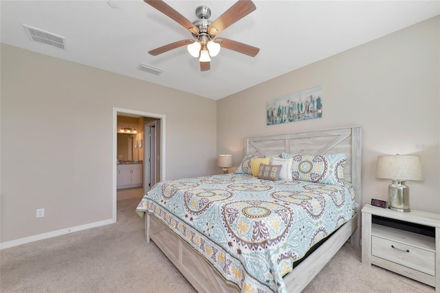 bedroom with ensuite bathroom, light carpet, and ceiling fan