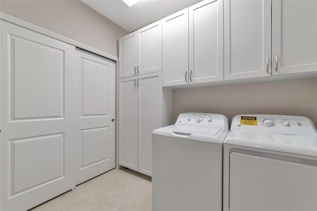 laundry area with cabinets, washing machine and dryer, and light tile patterned floors