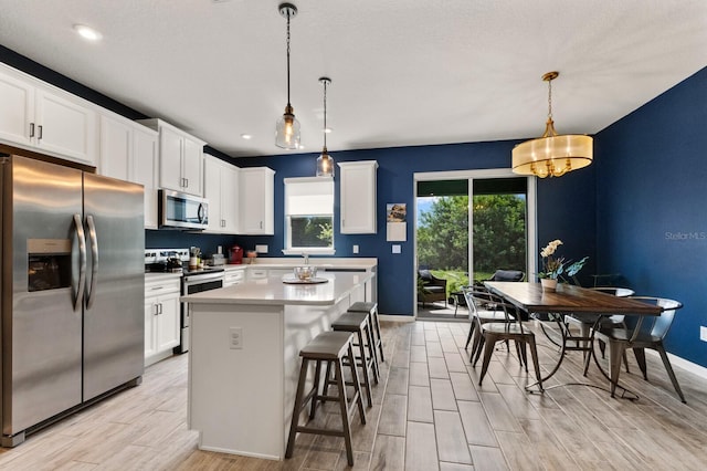 kitchen featuring white cabinets, pendant lighting, stainless steel appliances, and a kitchen island