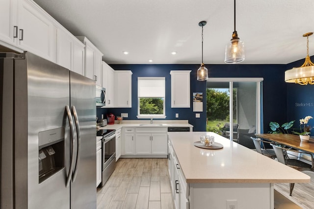 kitchen featuring decorative light fixtures, plenty of natural light, white cabinetry, and appliances with stainless steel finishes