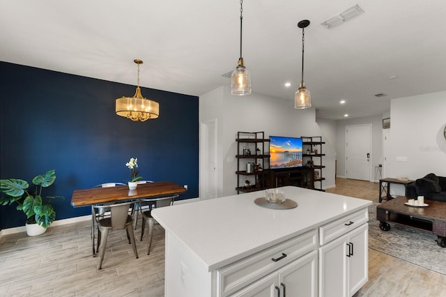 kitchen with white cabinetry, a center island, hanging light fixtures, and an inviting chandelier