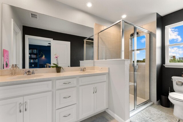 bathroom featuring vanity, toilet, and a shower with shower door