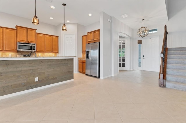 kitchen featuring stainless steel appliances, decorative backsplash, hanging light fixtures, light stone counters, and light tile patterned floors