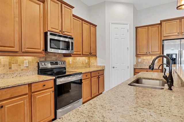 kitchen with appliances with stainless steel finishes, backsplash, light stone counters, and sink