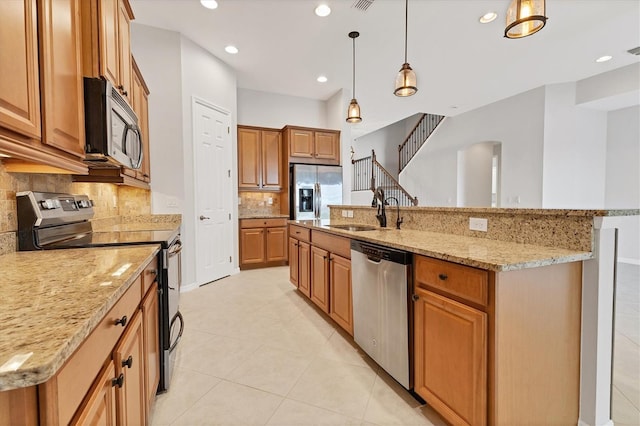 kitchen featuring appliances with stainless steel finishes, tasteful backsplash, decorative light fixtures, a kitchen island with sink, and sink