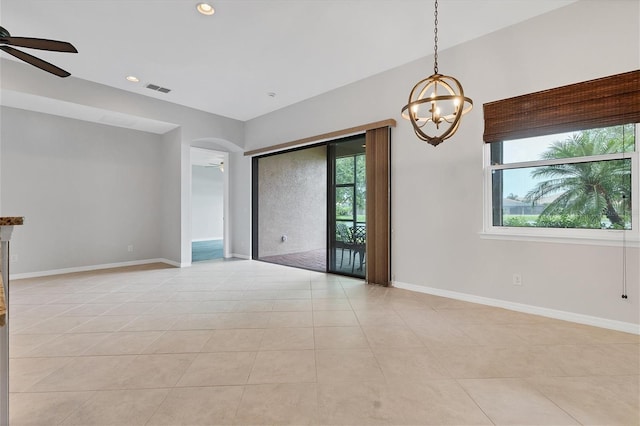 tiled empty room with ceiling fan with notable chandelier