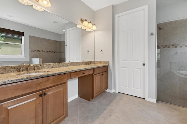 bathroom featuring tile patterned flooring, a tile shower, and vanity