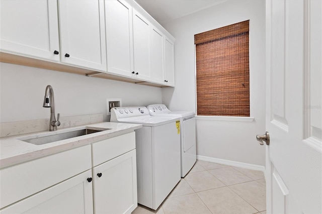 laundry area featuring cabinets, light tile patterned floors, washer and clothes dryer, and sink