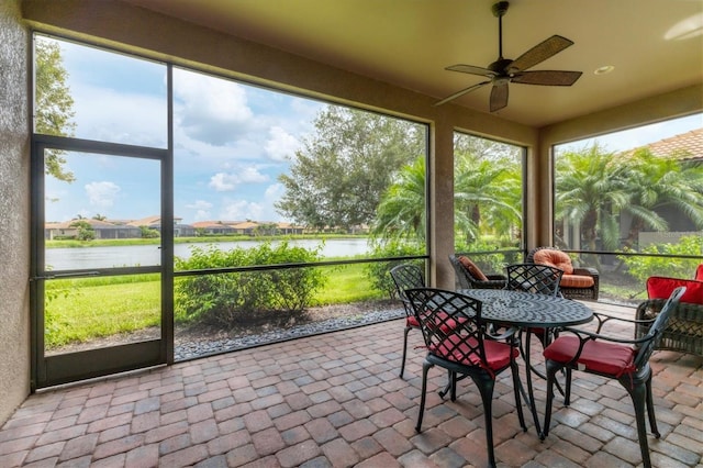 sunroom featuring ceiling fan and a water view