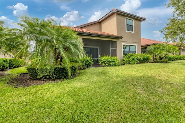 back of property with a sunroom and a lawn