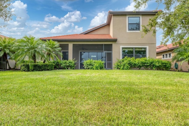 rear view of house featuring ceiling fan and a yard