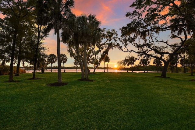 surrounding community with a water view and a yard