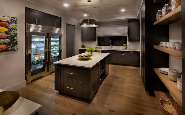 kitchen with sink, hanging light fixtures, wine cooler, light hardwood / wood-style flooring, and a kitchen island