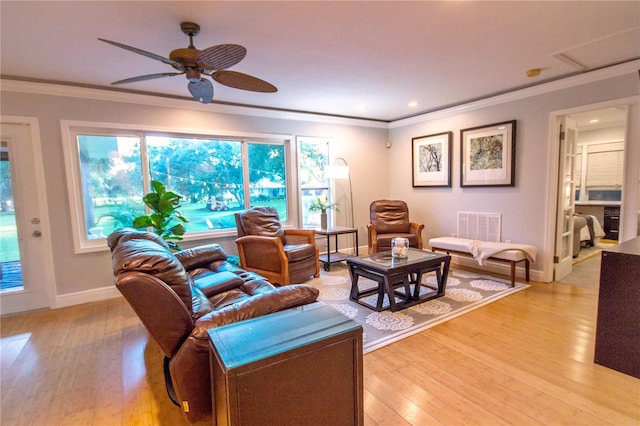 living room featuring a wealth of natural light, crown molding, ceiling fan, and light wood-type flooring