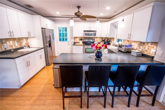 kitchen with a kitchen bar, kitchen peninsula, stainless steel appliances, and white cabinets