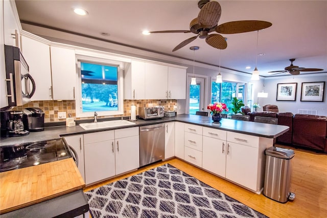 kitchen with sink, stainless steel appliances, light hardwood / wood-style flooring, kitchen peninsula, and white cabinets