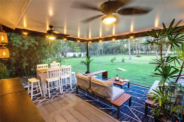 wooden terrace featuring an outdoor living space, ceiling fan, and a lawn