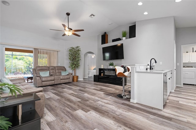 living room with ceiling fan, light wood-type flooring, washer / clothes dryer, and sink