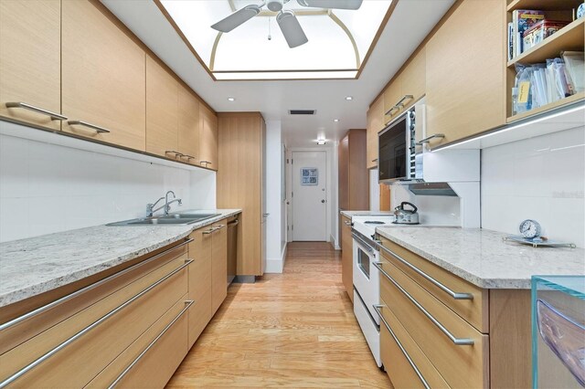 kitchen featuring sink, light stone counters, tasteful backsplash, dishwasher, and light hardwood / wood-style floors