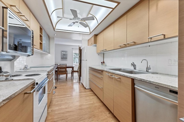 kitchen featuring sink, light hardwood / wood-style flooring, appliances with stainless steel finishes, light stone counters, and decorative backsplash