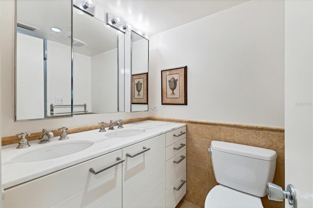 bathroom featuring vanity, tile walls, and toilet