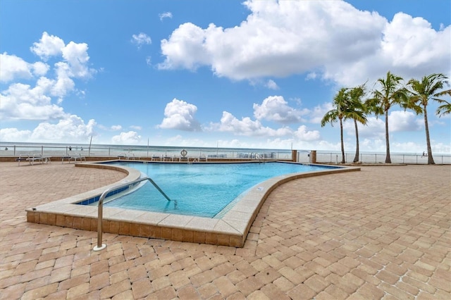 view of swimming pool with a patio area and a water view