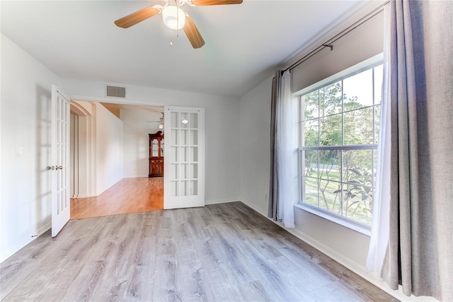 spare room featuring a healthy amount of sunlight, french doors, ceiling fan, and light hardwood / wood-style floors