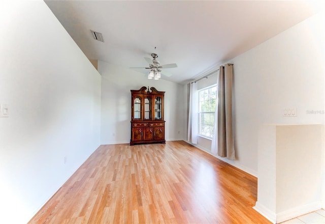 empty room with ceiling fan, light hardwood / wood-style floors, and vaulted ceiling