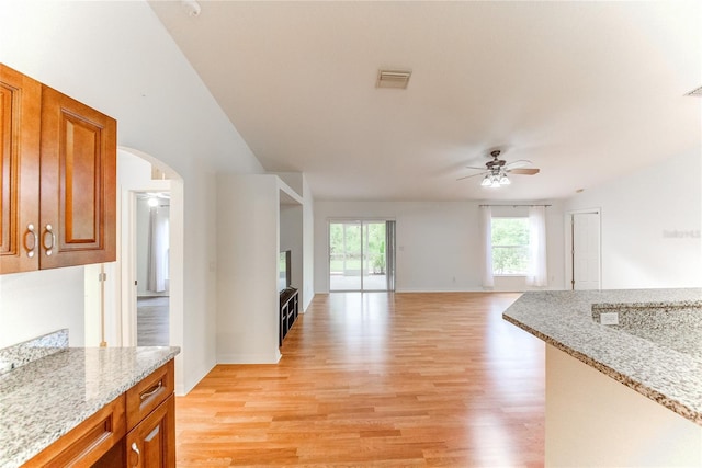 kitchen with ceiling fan, light hardwood / wood-style floors, and light stone counters