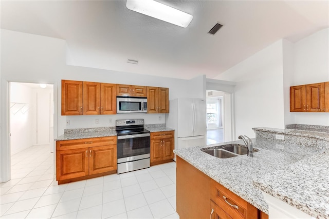 kitchen featuring light stone countertops, sink, light tile patterned floors, and stainless steel appliances