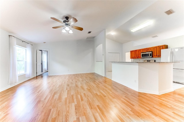 kitchen featuring lofted ceiling, light hardwood / wood-style flooring, ceiling fan, white fridge, and light stone counters