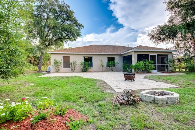 rear view of house featuring a patio area, a sunroom, a yard, and an outdoor fire pit