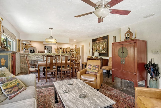 living room with ceiling fan and a textured ceiling