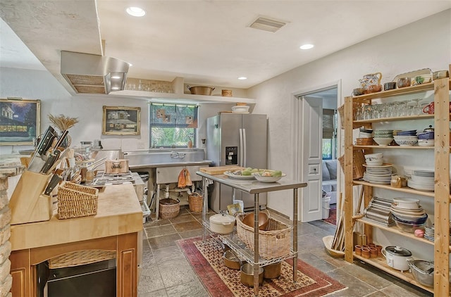 kitchen featuring stainless steel fridge with ice dispenser and ventilation hood