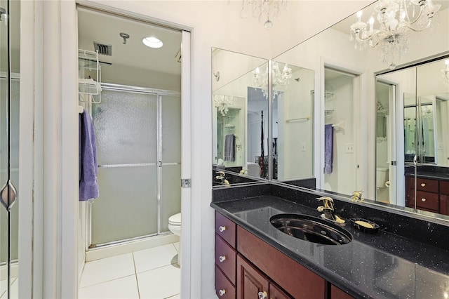 bathroom with a shower with shower door, tile patterned floors, toilet, vanity, and a chandelier