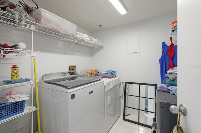 washroom with washing machine and clothes dryer, light tile patterned floors, and a textured ceiling