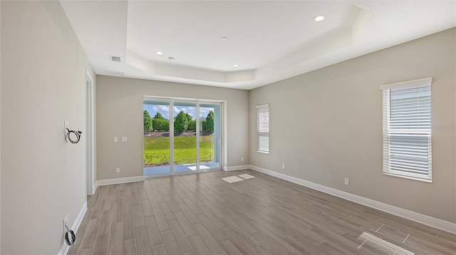 spare room with light hardwood / wood-style floors and a tray ceiling