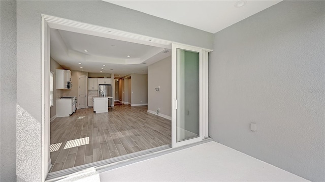 interior space featuring light wood-type flooring and a tray ceiling