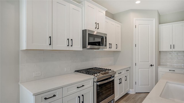 kitchen with sink, appliances with stainless steel finishes, white cabinets, and light stone counters