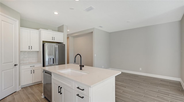 kitchen with sink, stainless steel appliances, white cabinets, an island with sink, and decorative backsplash