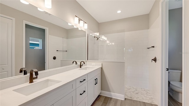 bathroom featuring a tile shower, vanity, and toilet