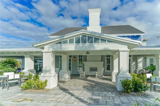 back of property with a fireplace and a patio area