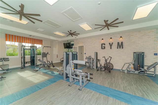 exercise room with ceiling fan, brick wall, and hardwood / wood-style floors